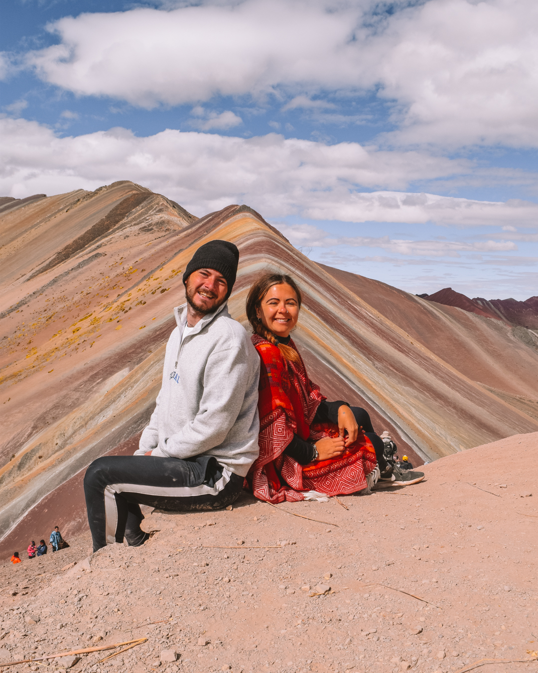 Two people sat overlooking the view of Rainbow Mountain