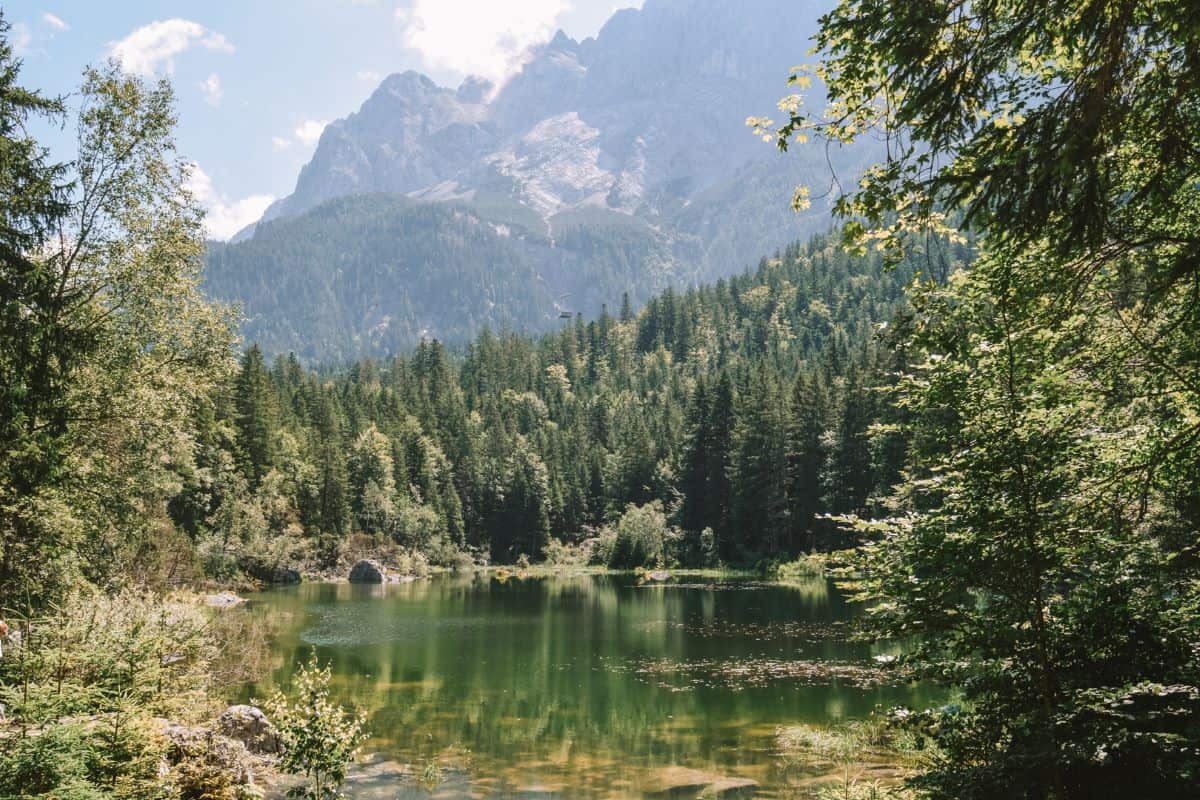 One of the smaller green lakes with reflections of the mountains in it and trees surrounding it.