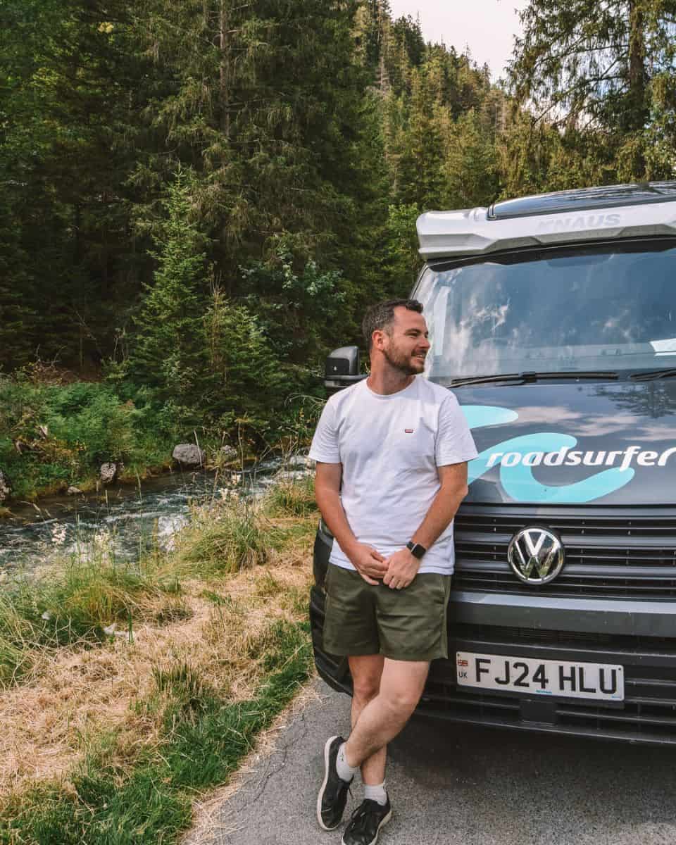 Chris stood outside the campervan by the stream