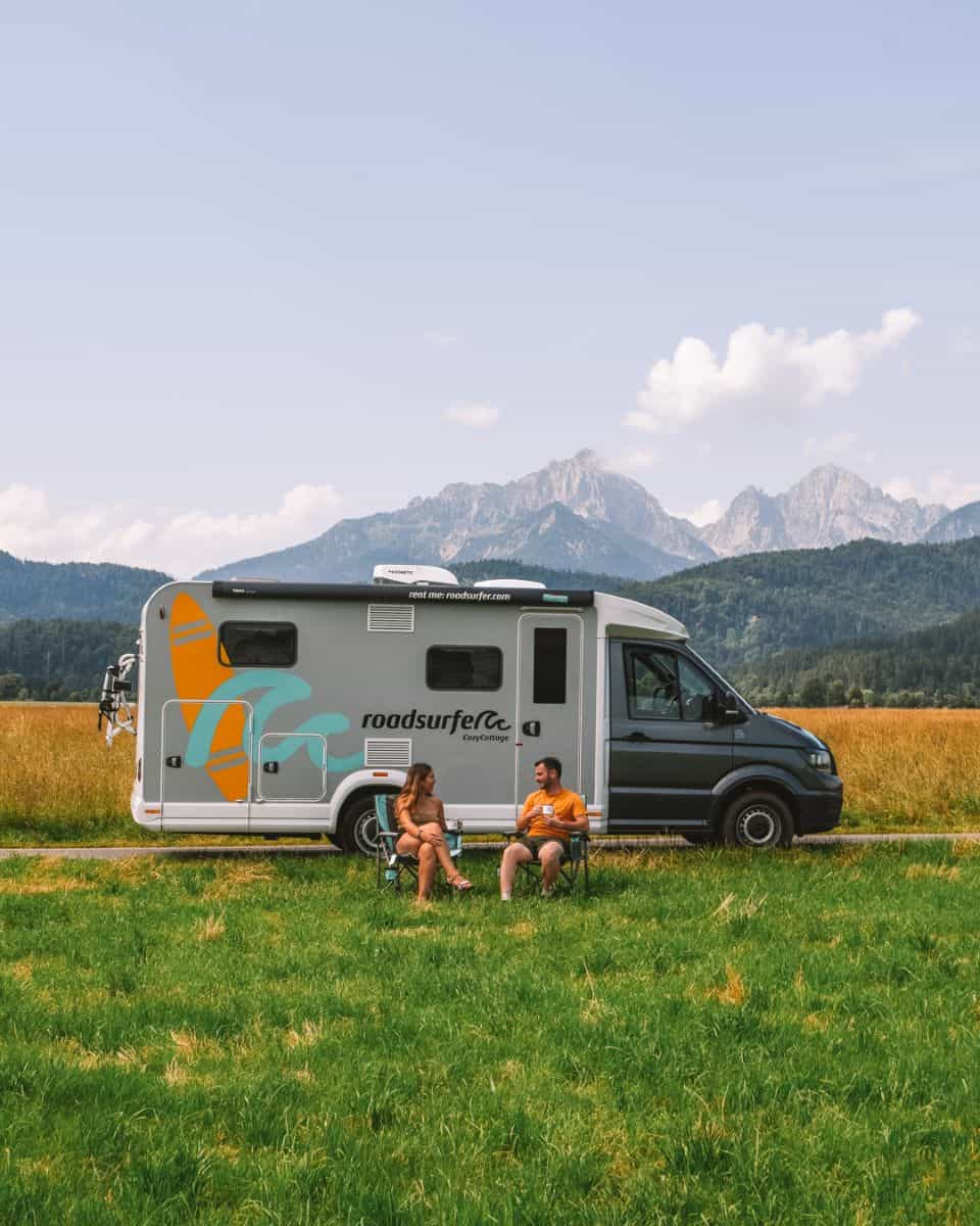 Reanna and Chris sitting outside their Roadsurfer campervan in Bavaria Germany