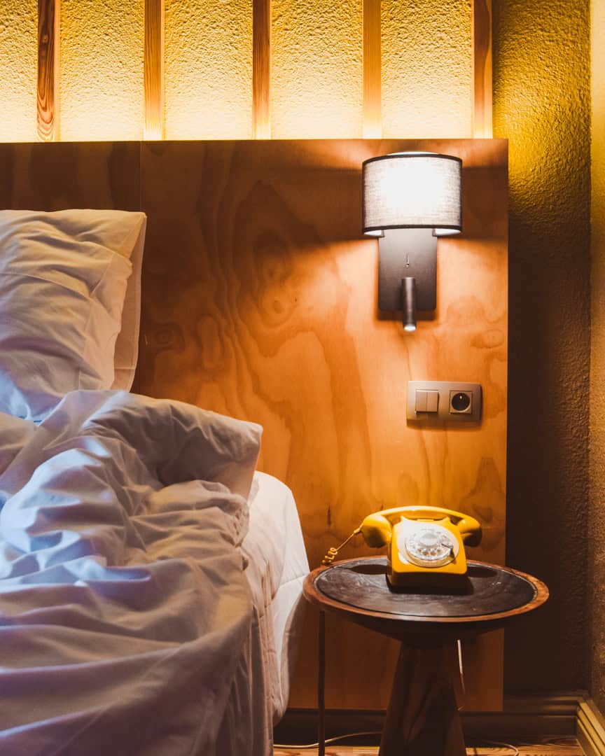 The bed, bedside table and yellow telephone at Hôtel Les Aiglons Chamonix